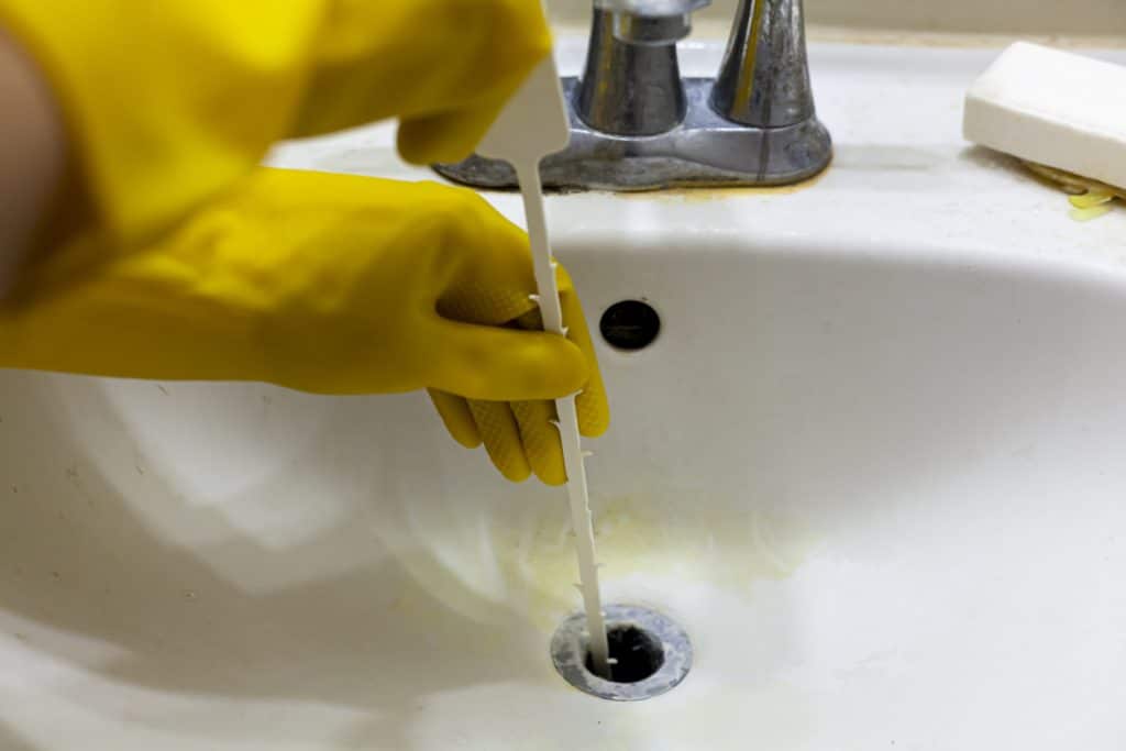 unclog the drain of a sink using snake auger tool